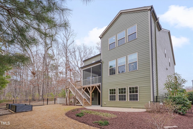 rear view of property featuring stairway, a patio area, fence, and a sunroom