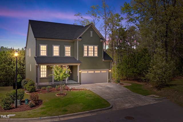 traditional-style home featuring a yard, an attached garage, a shingled roof, concrete driveway, and a porch