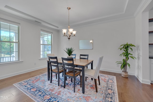 dining area with a chandelier, ornamental molding, visible vents, and wood finished floors
