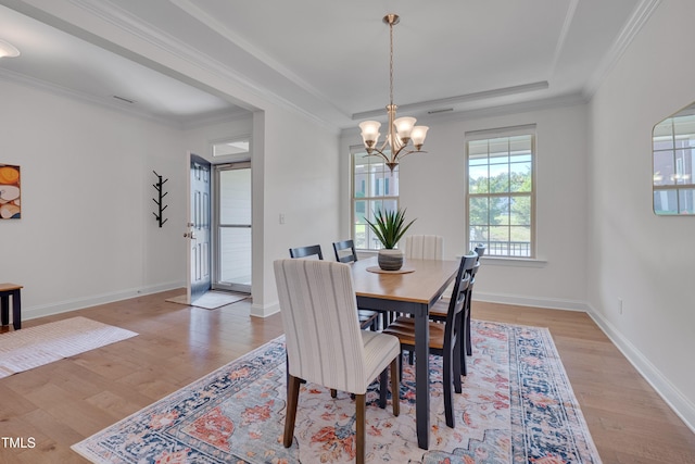 dining area with baseboards, ornamental molding, an inviting chandelier, and light wood-style flooring