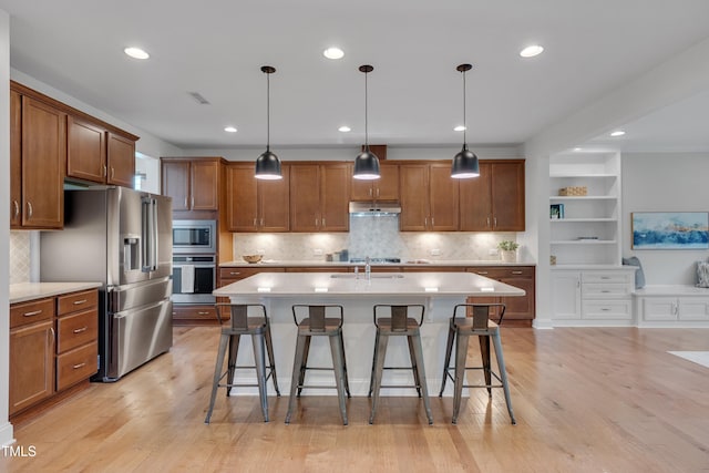 kitchen featuring stainless steel appliances, brown cabinets, a kitchen bar, and a sink