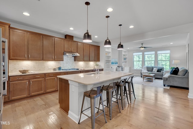 kitchen with recessed lighting, brown cabinetry, a breakfast bar, light wood-style floors, and light countertops