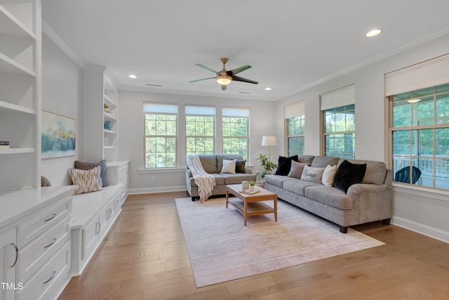 living area featuring a ceiling fan, a wealth of natural light, light wood-style floors, and crown molding