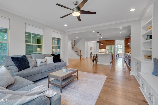 living room with a ceiling fan, light wood-type flooring, stairway, ornamental molding, and recessed lighting