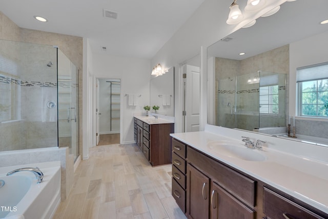 full bath with a stall shower, visible vents, a bath, vanity, and a spacious closet