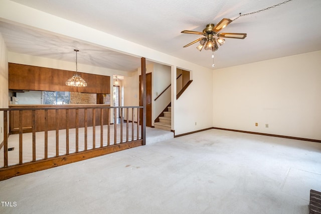 carpeted empty room with baseboards, stairway, and ceiling fan