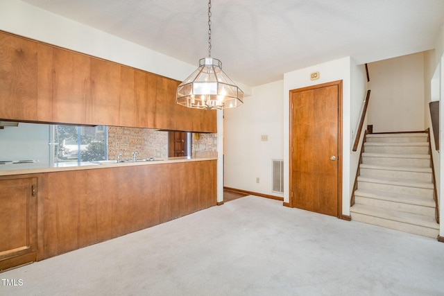 unfurnished dining area featuring a sink, carpet flooring, visible vents, stairs, and baseboards