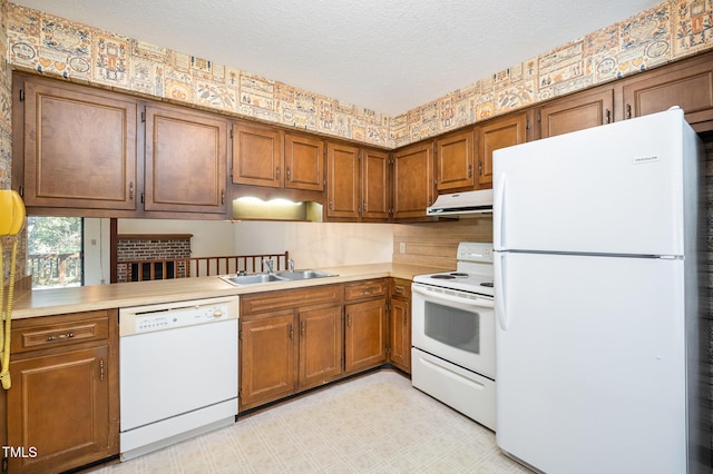 kitchen with light floors, a sink, a textured ceiling, white appliances, and under cabinet range hood