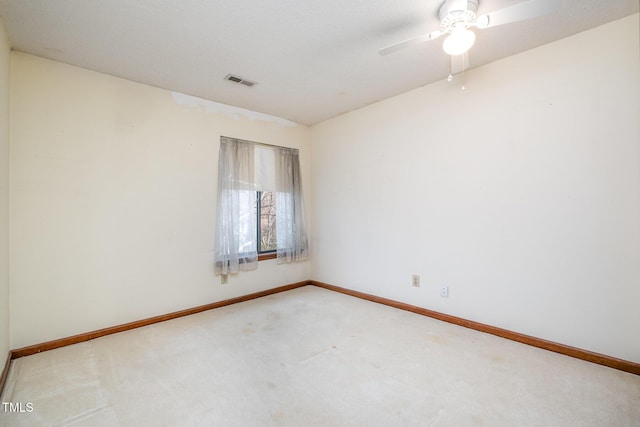 unfurnished room with a ceiling fan, light colored carpet, visible vents, and baseboards