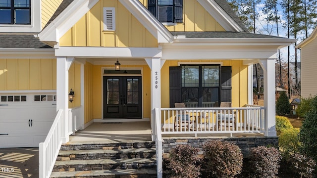 view of exterior entry featuring board and batten siding, covered porch, roof with shingles, and french doors