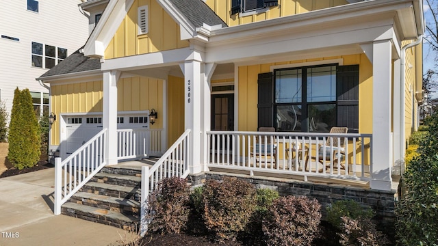 doorway to property with board and batten siding, covered porch, a shingled roof, and concrete driveway