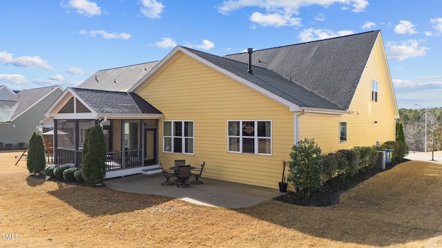 back of house with a sunroom, roof with shingles, and a patio