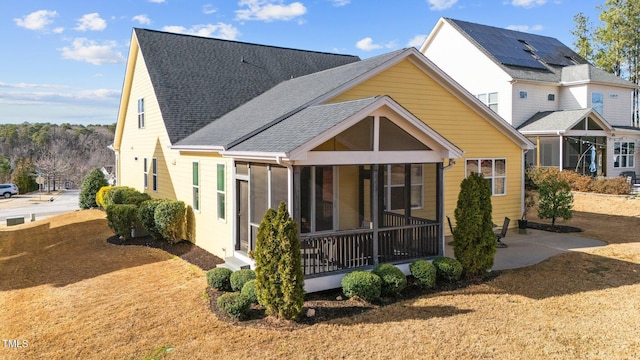 rear view of property with roof with shingles and a sunroom