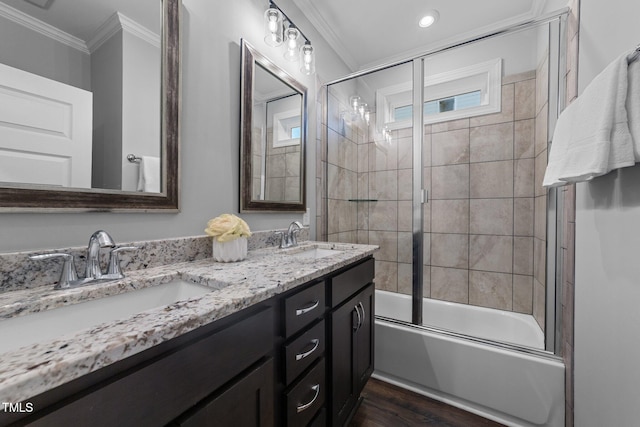 full bathroom featuring ornamental molding, bath / shower combo with glass door, a sink, and wood finished floors