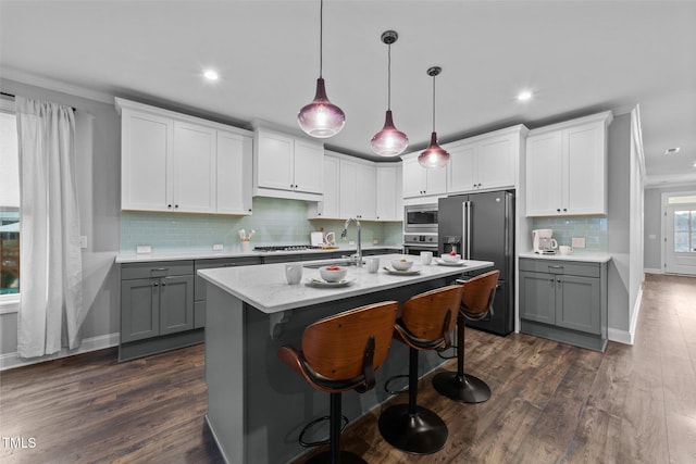 kitchen with stainless steel appliances, dark wood-style flooring, a kitchen island with sink, and gray cabinetry