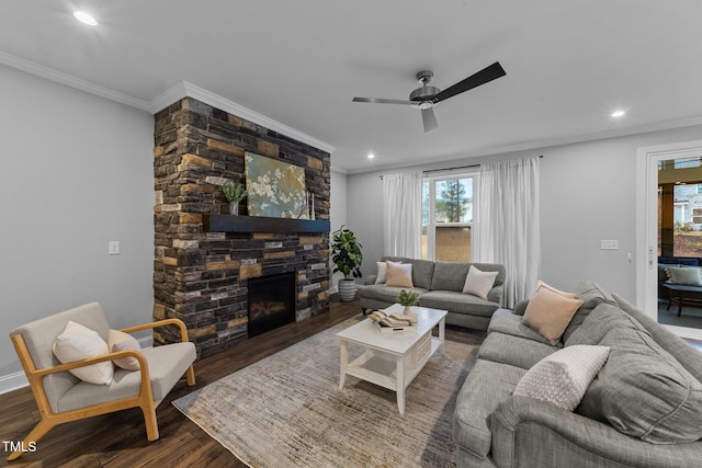 living area with recessed lighting, ornamental molding, ceiling fan, a stone fireplace, and wood finished floors