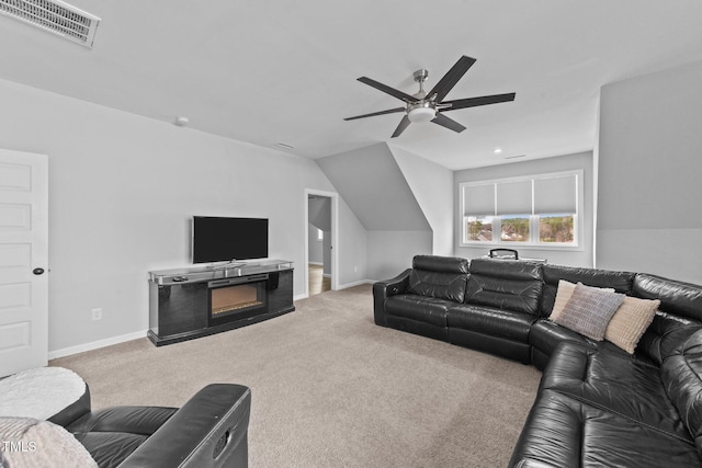 carpeted living room featuring lofted ceiling, visible vents, a ceiling fan, a glass covered fireplace, and baseboards