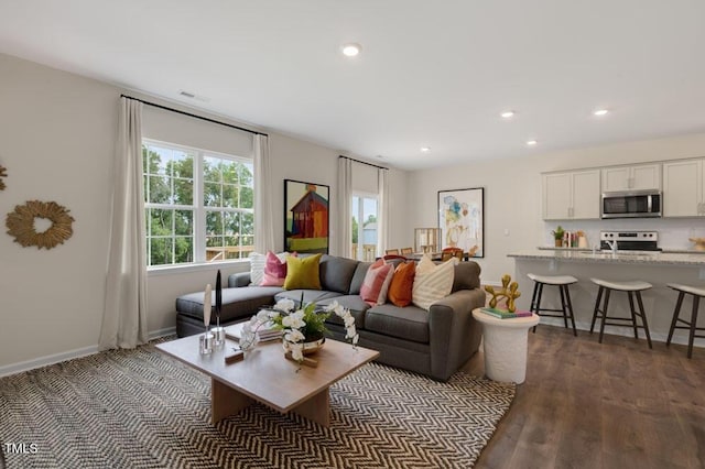 living room with visible vents, baseboards, dark wood-type flooring, and recessed lighting