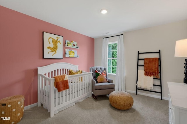 carpeted bedroom featuring a nursery area and baseboards