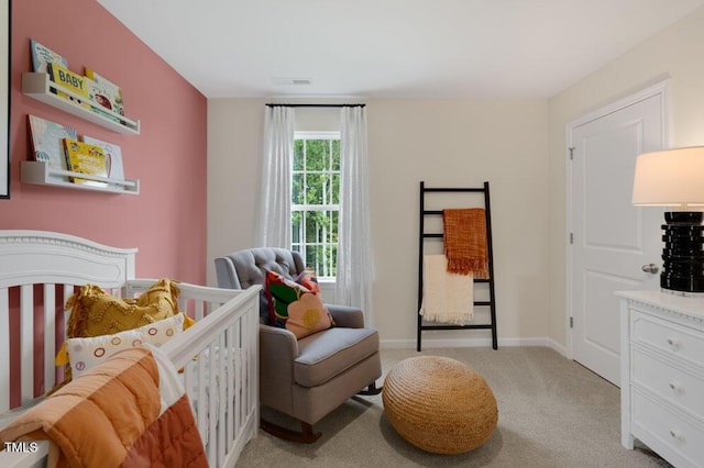 bedroom featuring baseboards, a nursery area, and light colored carpet