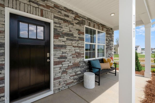 property entrance with stone siding and a porch