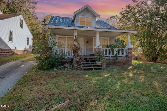 view of front of home featuring metal roof, a porch, and a front lawn