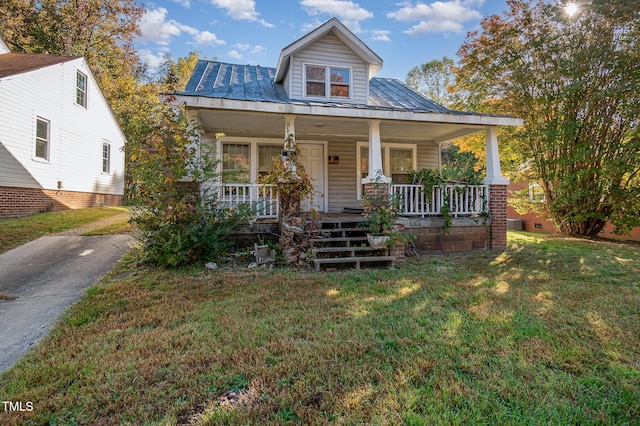 view of front facade with metal roof, a front lawn, a porch, and a standing seam roof