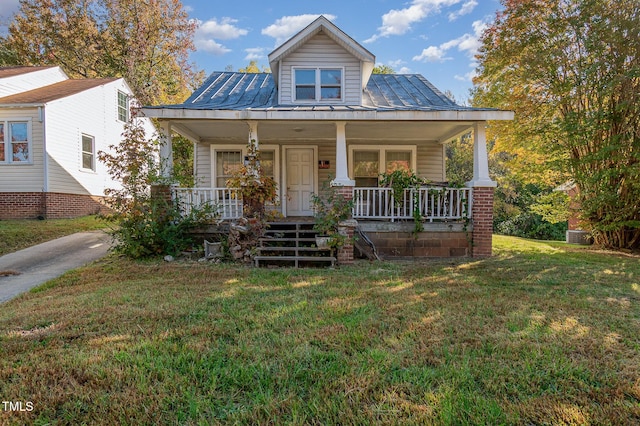 view of front of house featuring a porch, a standing seam roof, metal roof, and a front lawn