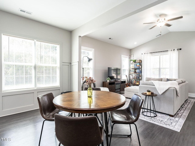 dining room featuring vaulted ceiling, dark wood-style flooring, wainscoting, and a decorative wall