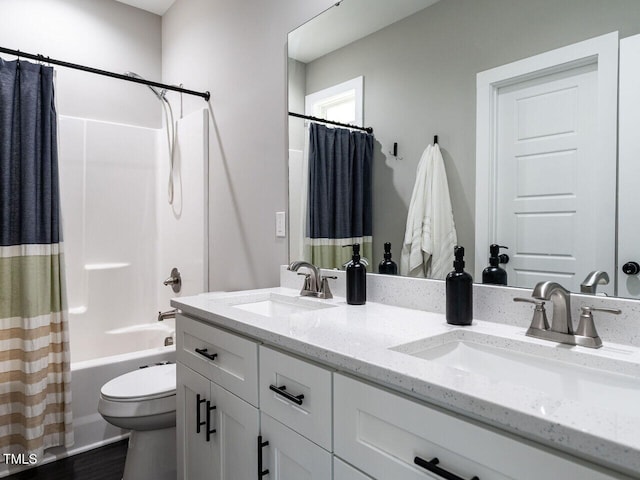 bathroom featuring double vanity, shower / tub combo, a sink, and toilet