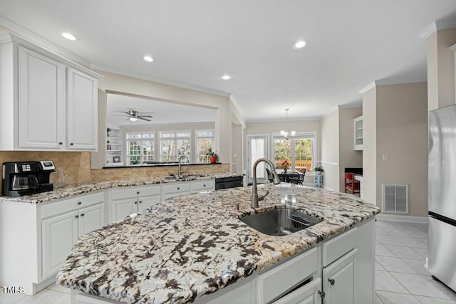 kitchen featuring crown molding, freestanding refrigerator, visible vents, and a sink