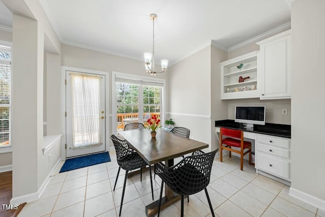 dining room featuring light tile patterned floors, a chandelier, baseboards, built in desk, and crown molding