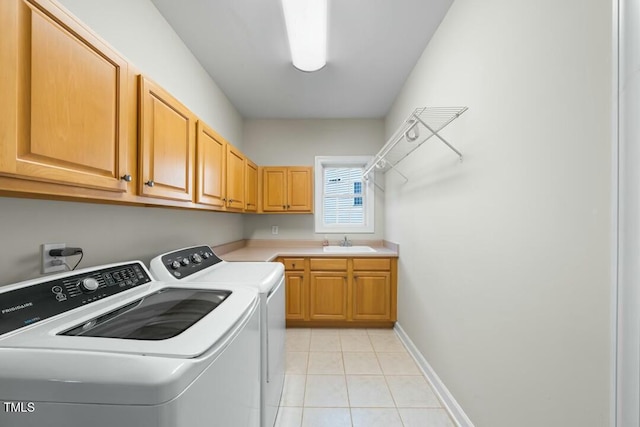 washroom featuring light tile patterned floors, washing machine and dryer, a sink, baseboards, and cabinet space