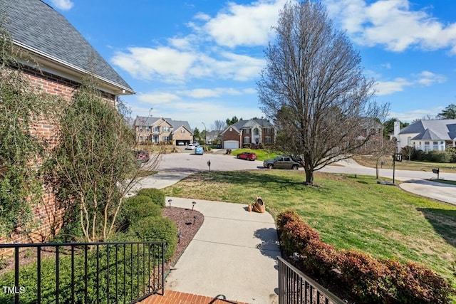 view of property's community with a residential view, fence, and a lawn