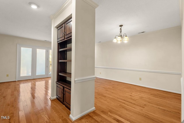 hallway with baseboards, ornamental molding, light wood-style flooring, and an inviting chandelier