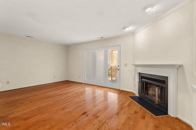 unfurnished living room featuring visible vents, baseboards, a fireplace with flush hearth, light wood-style flooring, and ornamental molding