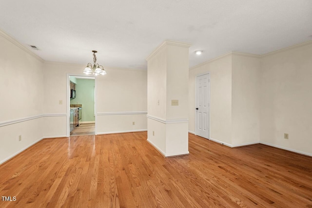 empty room featuring baseboards, visible vents, crown molding, and light wood finished floors