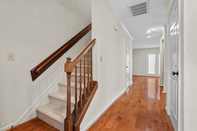 hallway featuring crown molding, visible vents, stairway, light wood-style flooring, and baseboards