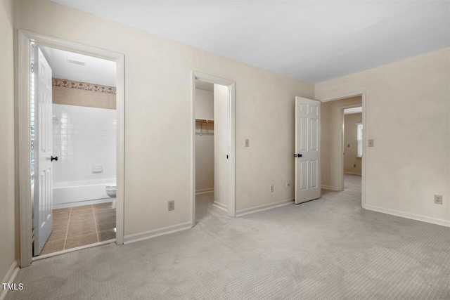 unfurnished bedroom featuring a closet, visible vents, a spacious closet, carpet flooring, and baseboards