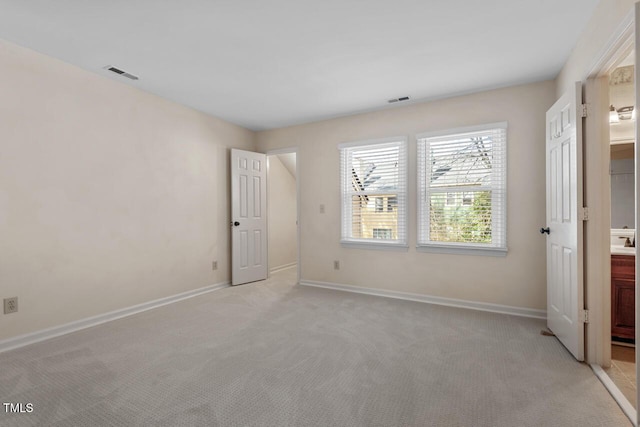 unfurnished bedroom with visible vents, ensuite bath, light carpet, and baseboards