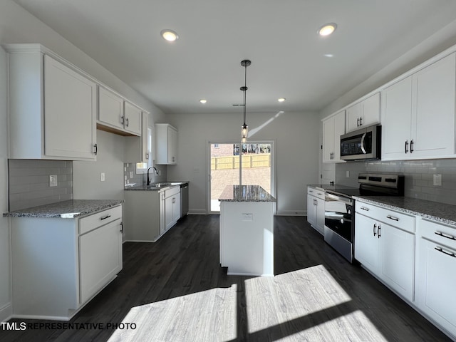 kitchen featuring a kitchen island, appliances with stainless steel finishes, white cabinets, and light stone counters