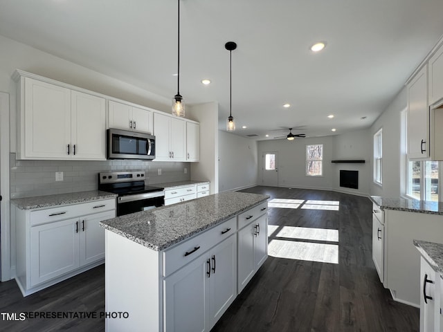 kitchen featuring white cabinets, a kitchen island, stainless steel appliances, and dark wood-style flooring