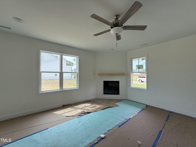 394 Springtooth Dr, Zebulon, NC 27597 - unfurnished living room featuring a glass covered fireplace and a ceiling fan