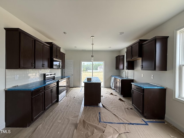 394 Springtooth Dr, Zebulon, NC 27597 - kitchen with appliances with stainless steel finishes, dark brown cabinetry, a kitchen island, and decorative backsplash