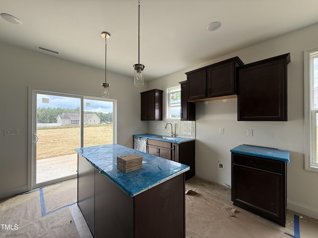394 Springtooth Dr, Zebulon, NC 27597 - kitchen with dark brown cabinets, plenty of natural light, a kitchen island, and backsplash