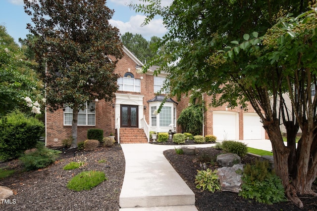 view of front of house featuring a garage, driveway, french doors, and brick siding