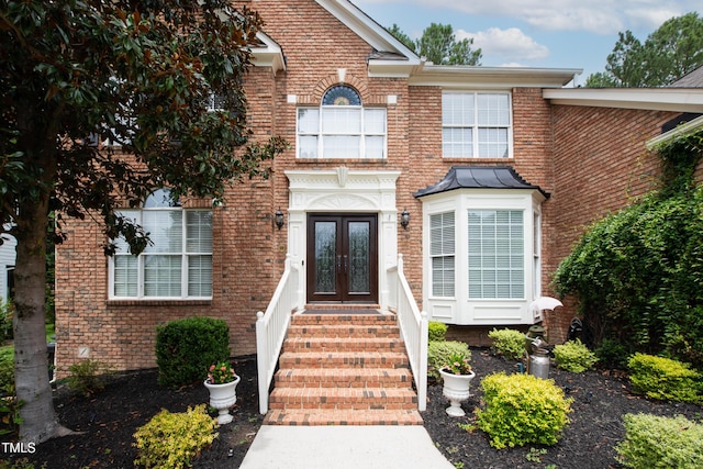 view of exterior entry featuring french doors and brick siding