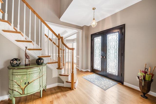 foyer entrance featuring french doors, stairway, wood finished floors, and baseboards