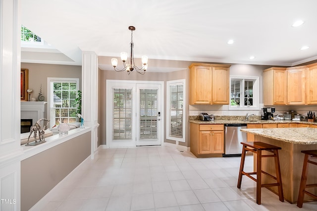 kitchen featuring light brown cabinets, light stone countertops, dishwasher, a glass covered fireplace, and crown molding