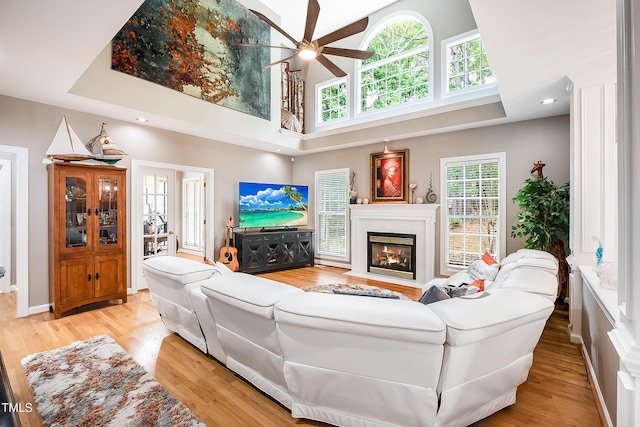 living area with light wood-type flooring, a fireplace with flush hearth, and a wealth of natural light